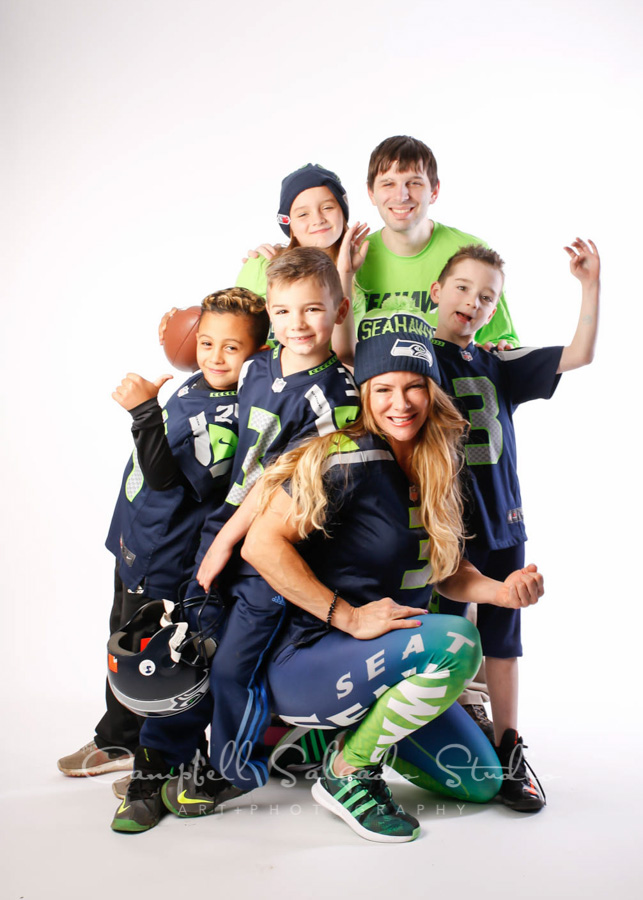  Portrait of family in football gear on white background by family photographers at Campbell Salgado Studio in Portland, Oregon. 