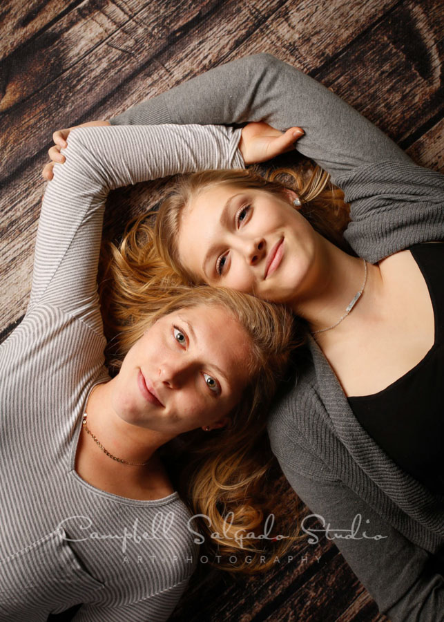  Portrait of sisters on wooden floor background by family photographers at Campbell Salgado Studio in Portland, Oregon. 