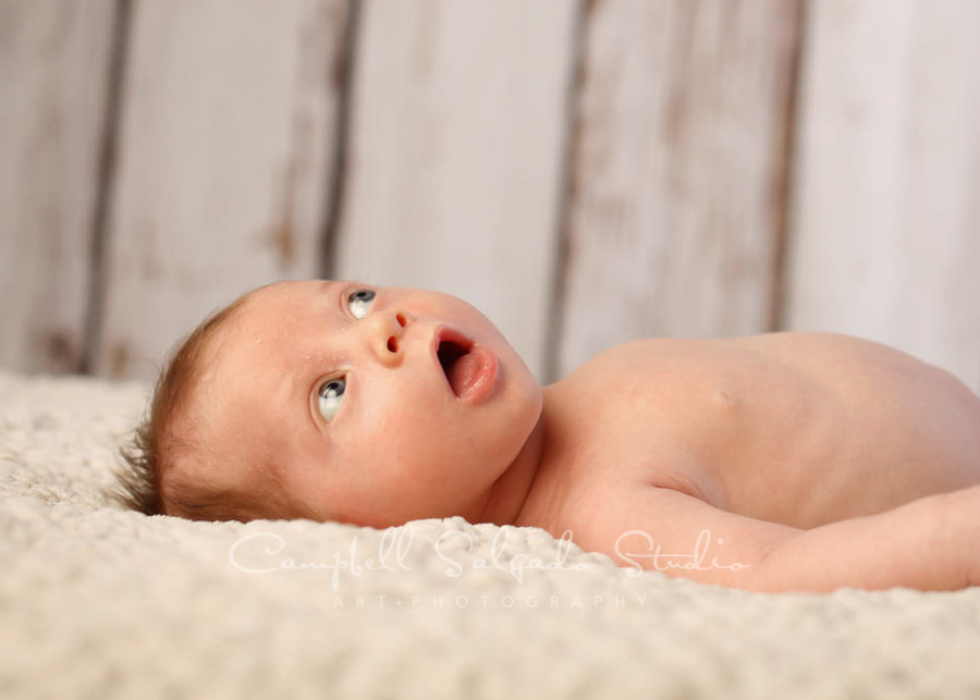  Portraits of infant on white fenceboards background by infant photographers at Campbell Salgado Studio in Portland, Oregon. 