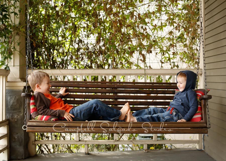  Portrait of kids on porch swing background by children's photographers at Campbell Salgado Studio in Portland, Oregon. 