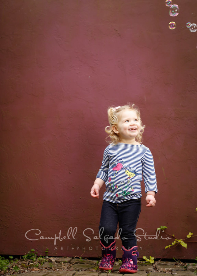  Portrait of toddler on plum stucco background by child photographers at Campbell Salgado Studio in Portland, Oregon. 