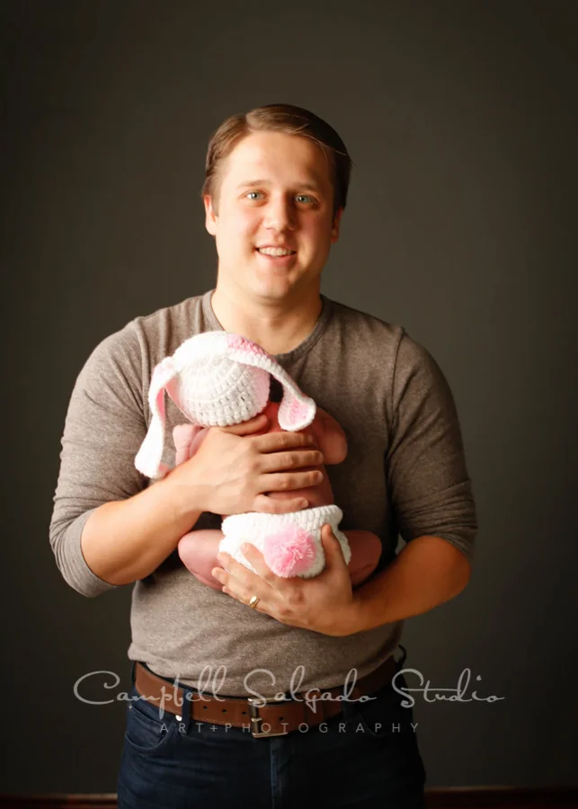 Portrait of father and baby on gray background by newborn photographers at Campbell Salgado Studio in Portland, Oregon.