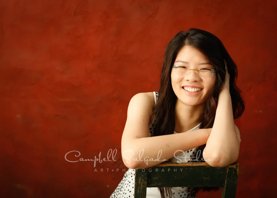 Portrait of teen on red stucco background by teen photographers at Campbell Salgado Studio in Portland, Oregon.
