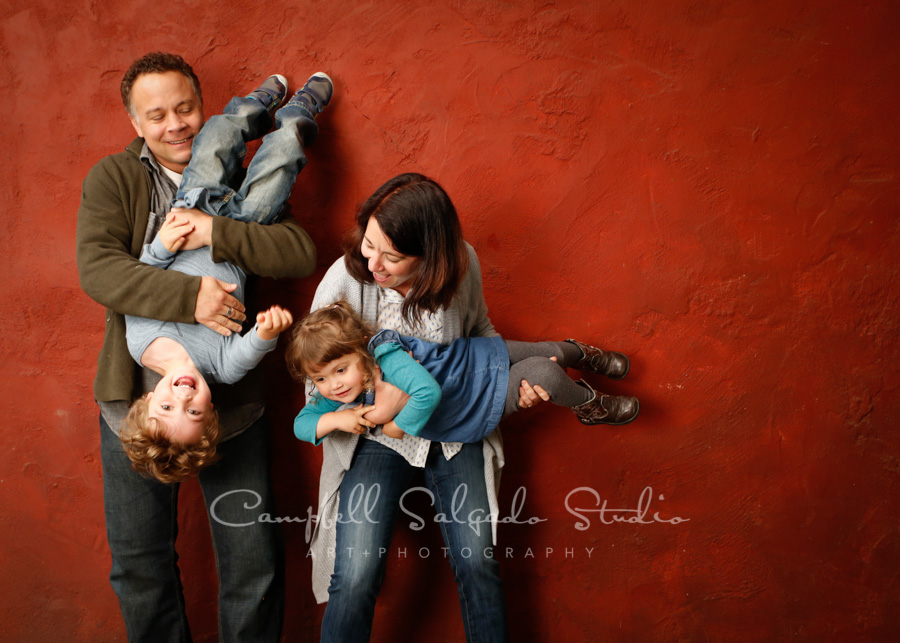  Portrait of family on red stucco background by family photographers at Campbell Salgado Studio. 