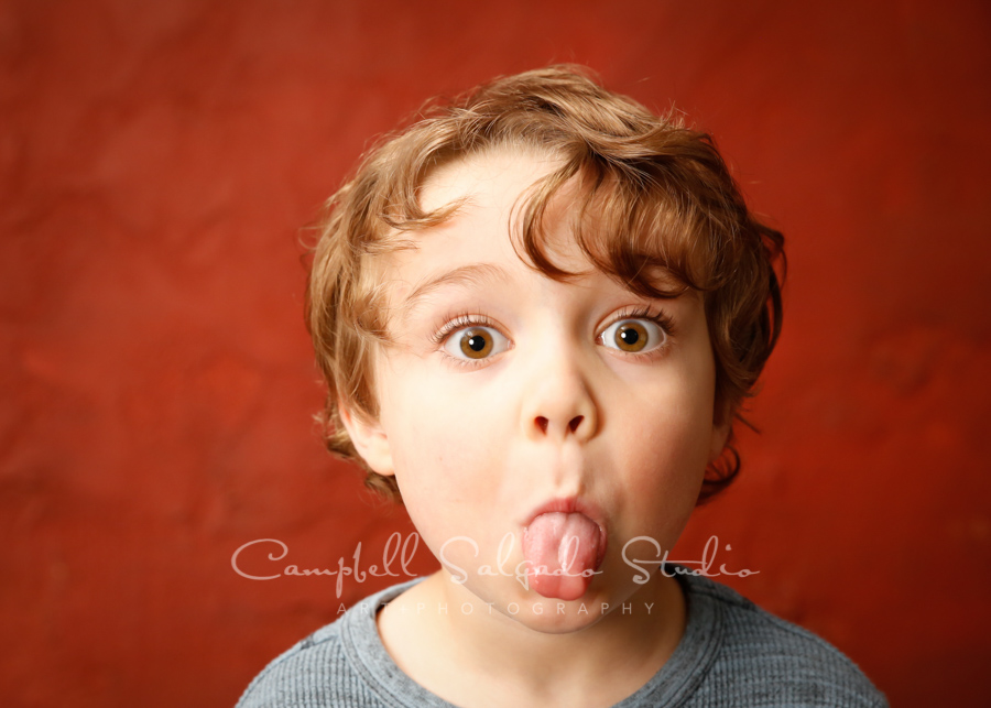  Portrait of boy on red stucco background by child photographers at Campbell Salgado Studio. 