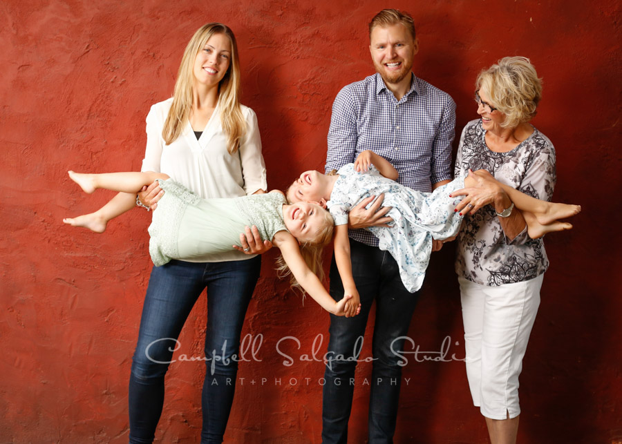  Portrait of multi- generational family on red stucco background by family photographers at Campbell Salgado Studio in Portland, Oregon. 