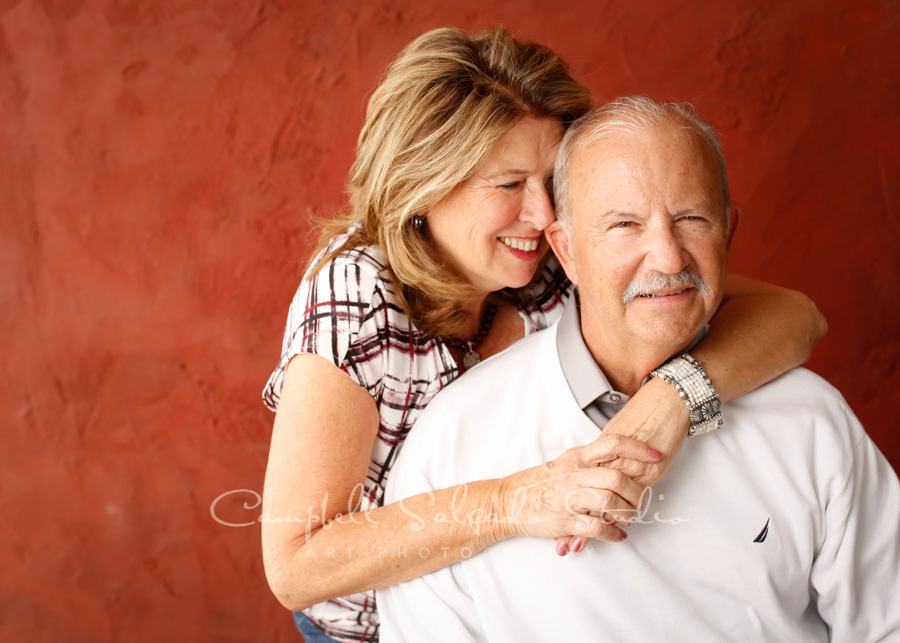  Portrait of couple on red stucco background by couple photographers at Campbell Salgado Studio in Portland, Oregon. 