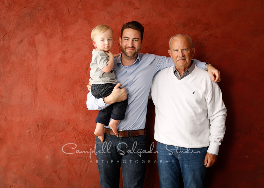  Portrait of multi-generational family on red stucco background by family photographers at Campbell Salgado Studio in Portland, Oregon. 