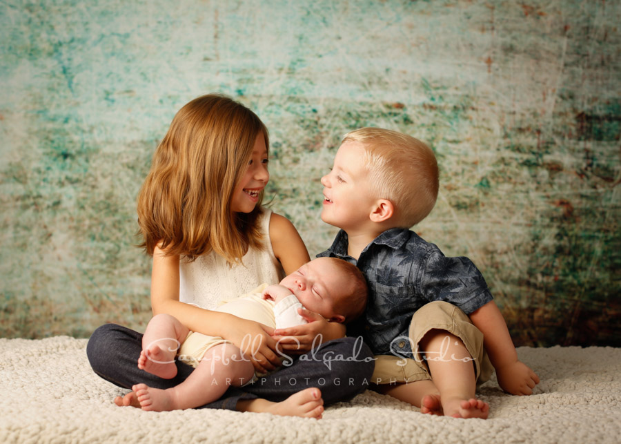  Portrait of kids on weathered green background by childrens photographers at Campbell Salgado Studio in Portland, Oregon. 