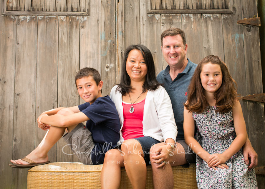  Portrait of family on old barn doors background by family photographers at Campbell Salgado Studio in Portland, Oregon. 