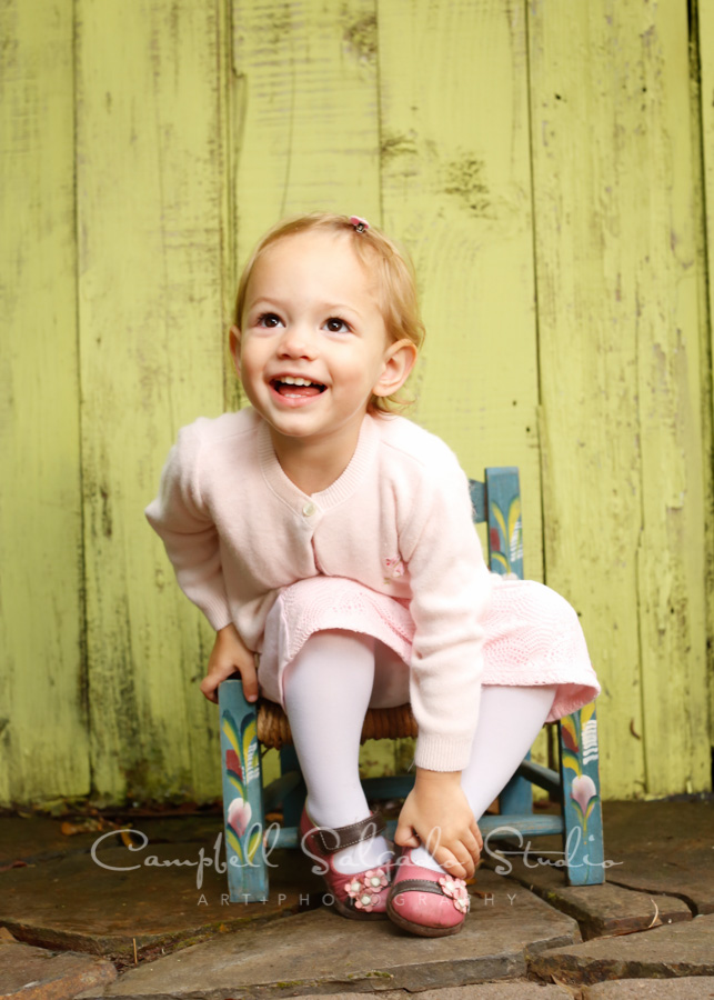 Portrait of child on lime fenceboards background by child photographers at Campbell Salgado Studio in Portland, Oregon.