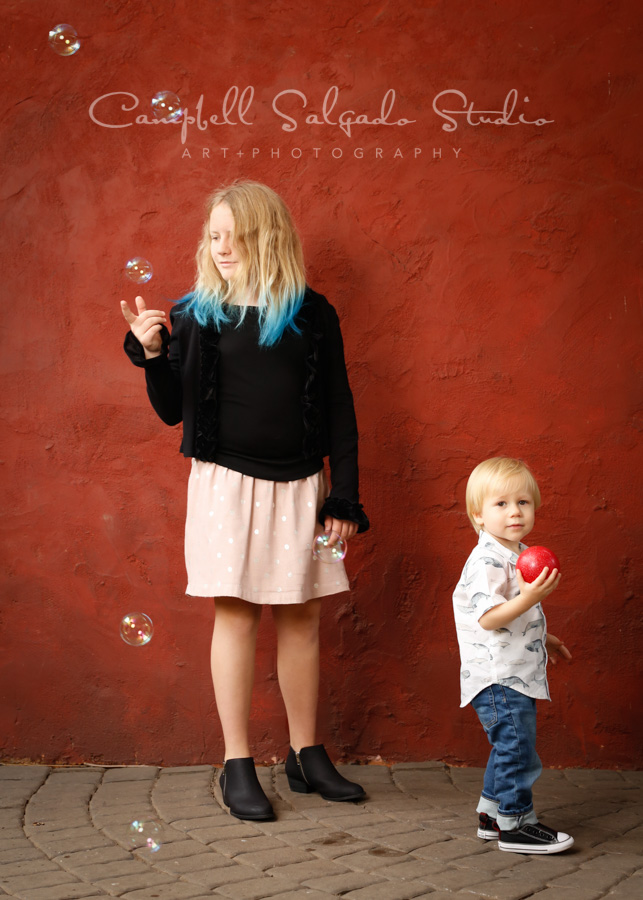  Portrait of family on red stucco background by family photographers at Campbell Salgado Studio in Portland, Oregon. 