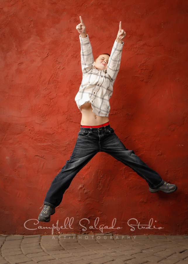  Portrait of boy on red stucco background by child photographers at Campbell Salgado Studio in Portland, Oregon. 