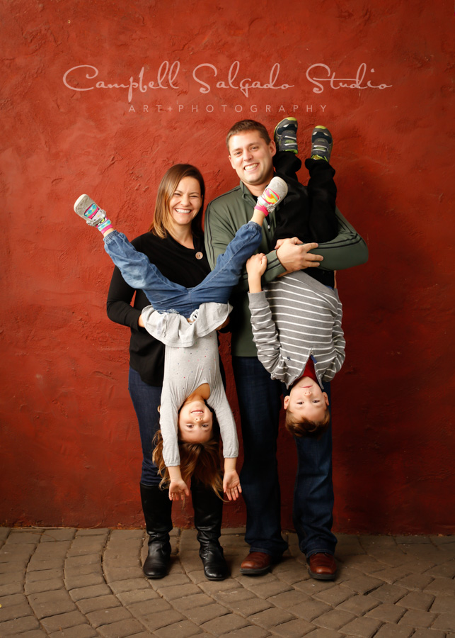  Portrait of family on red stucco background by family photographers at Campbell Salgado Studio in Portland, Oregon. 