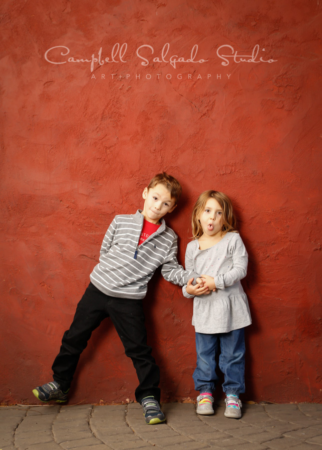  Portrait of kids on red stucco background by child photographers at Campbell Salgado Studio in Portland, Oregon. 