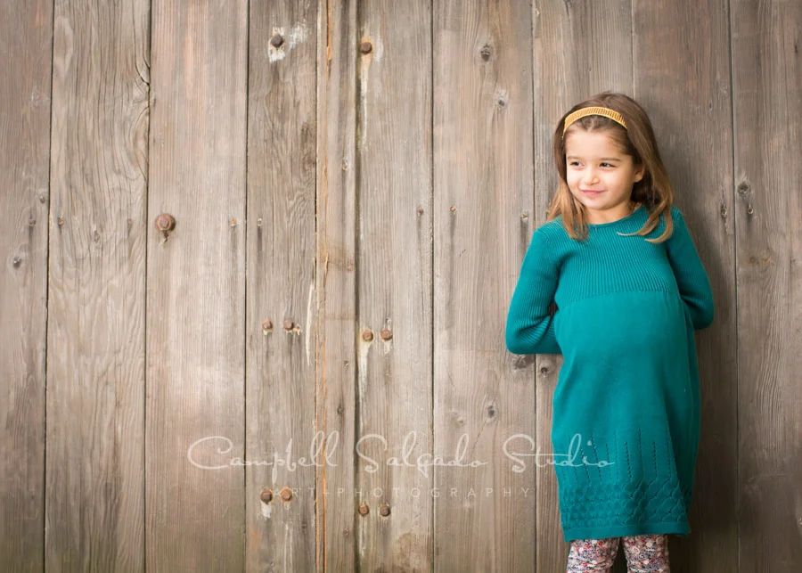 Portrait of girl on old doors background by child photographers at Campbell Salgado Studio in Portland, Oregon.