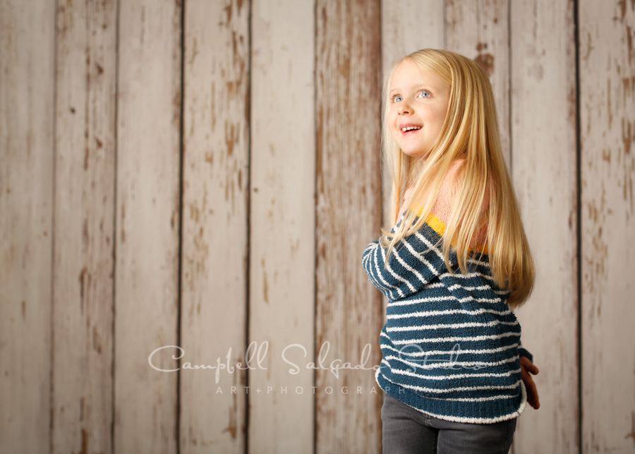  Portrait of girl on white fenceboards background by children's photographers at Campbell Salgado Studio in Portland, Oregon. 