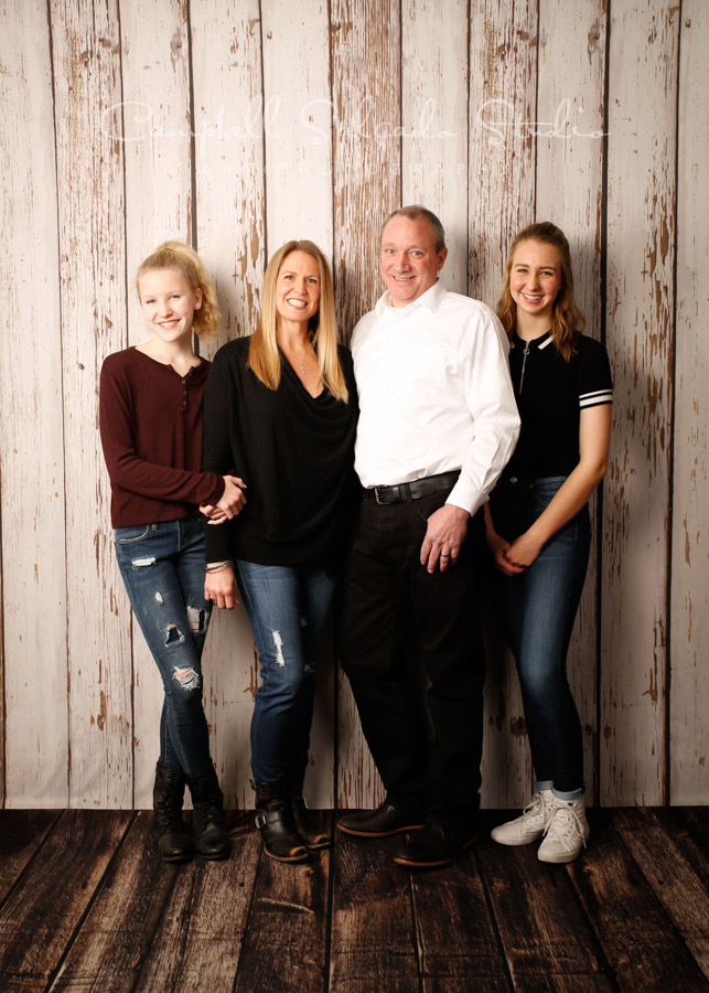 Portrait of family on white fenceboards background by family photographers at Campbell Salgado Studio in Portland, Oregon.