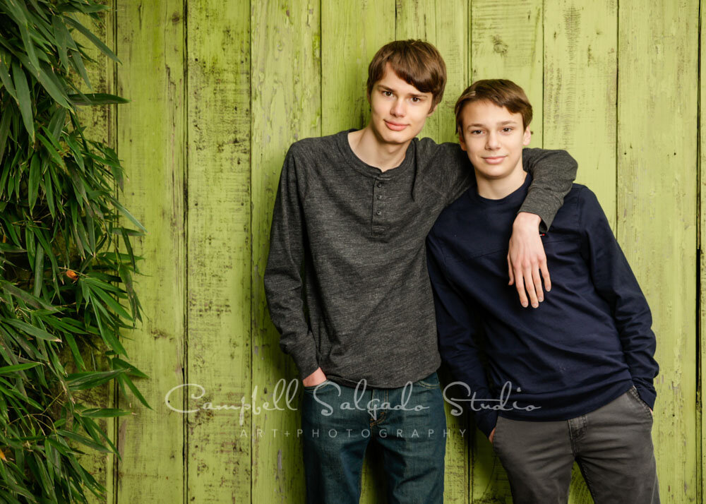  Portrait of brothers on lime fenceboards background by teen photographers at Campbell Salgado Studio in Portland, Oregon. 