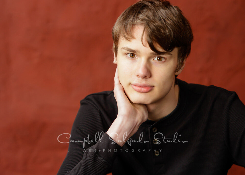  Portrait of teen on red stucco background by teen photographers at Campbell Salgado Studio in Portland, Oregon. 