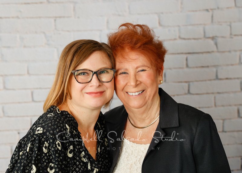  Portrait of mother and daughter on ivory brick background by family photographers at Campbell Salgado Studio in Portland, Oregon. 