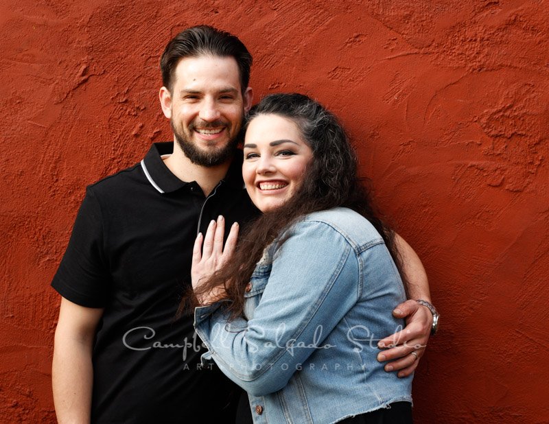  Portrait of couple on red stucco background by couples photographers at Campbell Salgado Studio in Portland, Oregon. 