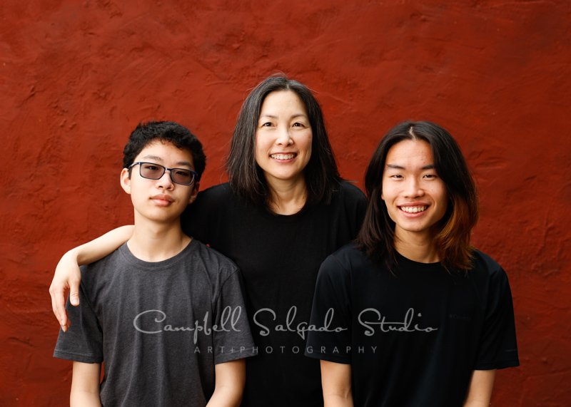  Portrait of family on red stucco background by family photographers at Campbell Salgado Studio in Portland, Oregon. 