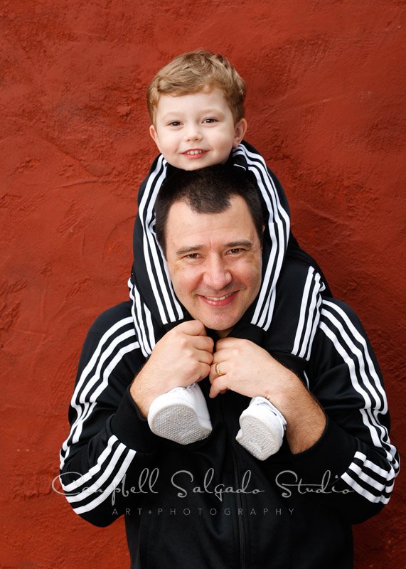  Portrait of family on red stucco background by family photographers at Campbell Salgado Studio in Portland, Oregon. 