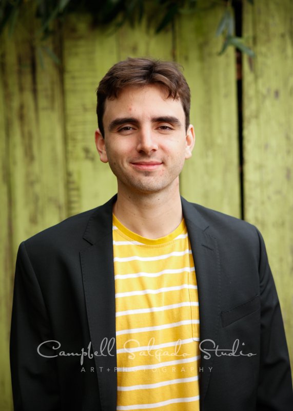  Portrait of college senior on lime fenceboards background by individual photographers at Campbell Salgado Studio in Portland, Oregon. 