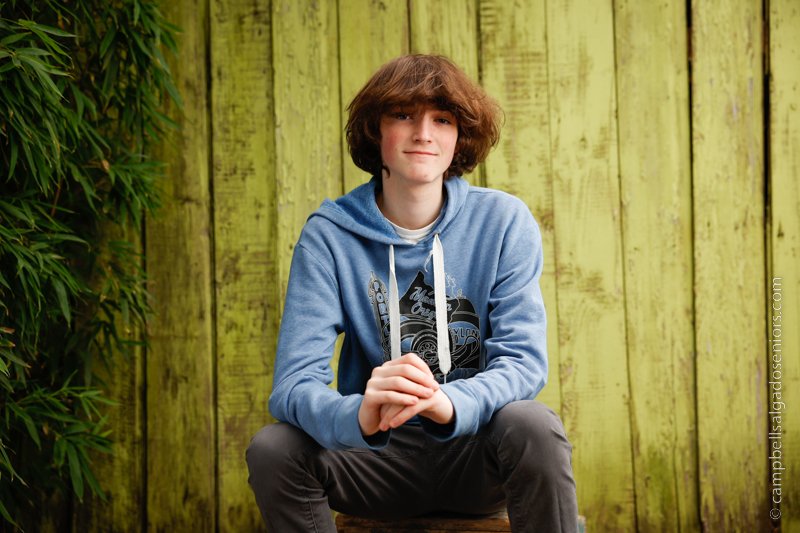  Portrait of teen on lime fenceboards background by teen photographers at Campbell Salgado Studio in Portland, Oregon. 