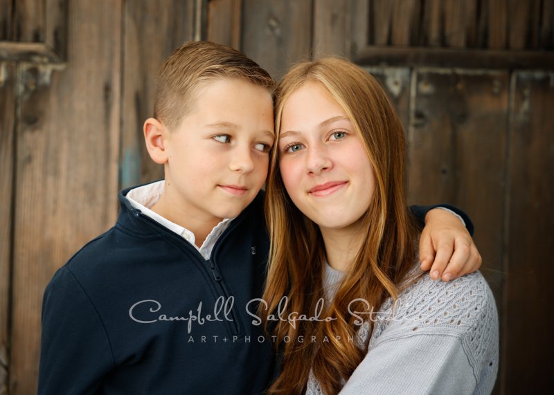  Portrait of siblings on barn doors background by child photographers at Campbell Salgado Studio in Portland, Oregon. 