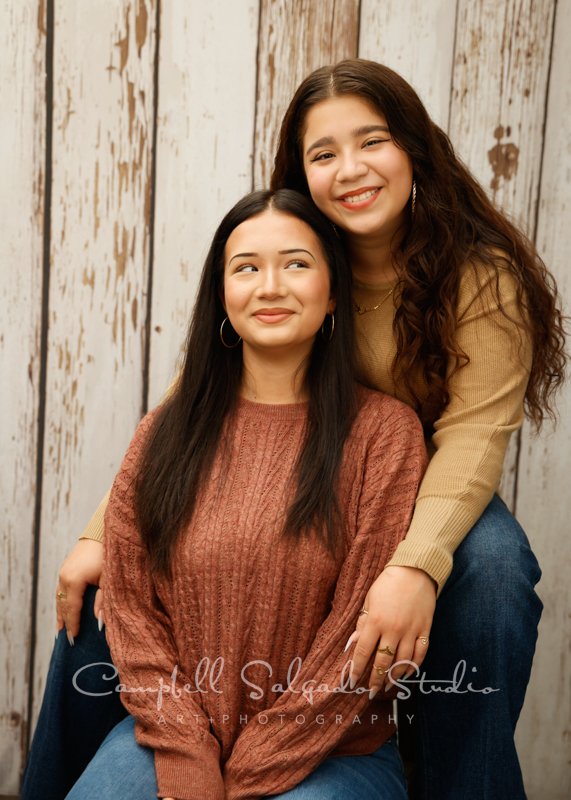  Portrait of sisters on white fenceboards background by teen photographers at Campbell Salgado Studio in Portland, Oregon. 