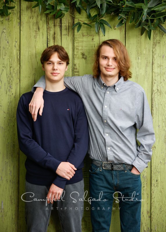  Portrait of brothers on lime fenceboards background by family photographers at Campbell Salgado Studio in Portland, Oregon. 
