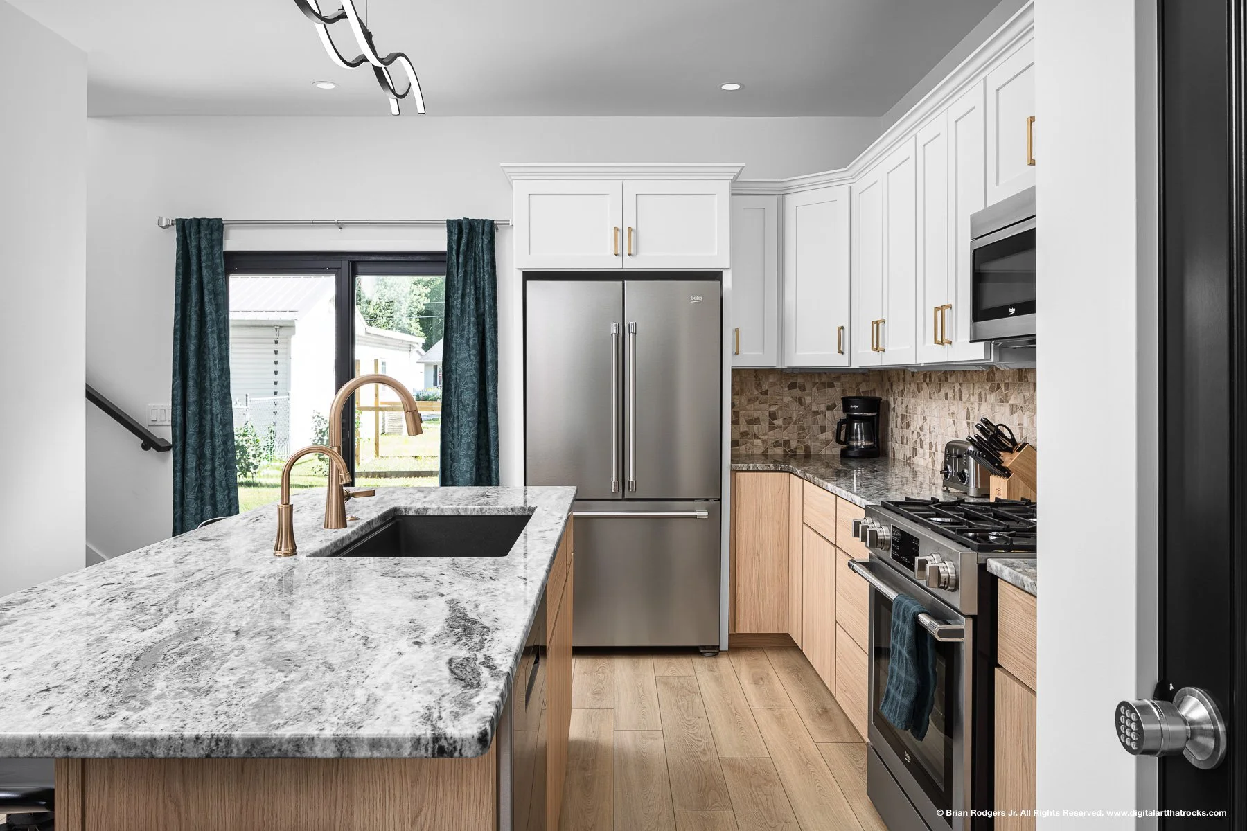 Interior architectural photography of a modern kitchen featuring custom white cabinetry, gold fixtures, and stone countertops in Warsaw, Indiana, highlighting millwork and interior design for custom builders.