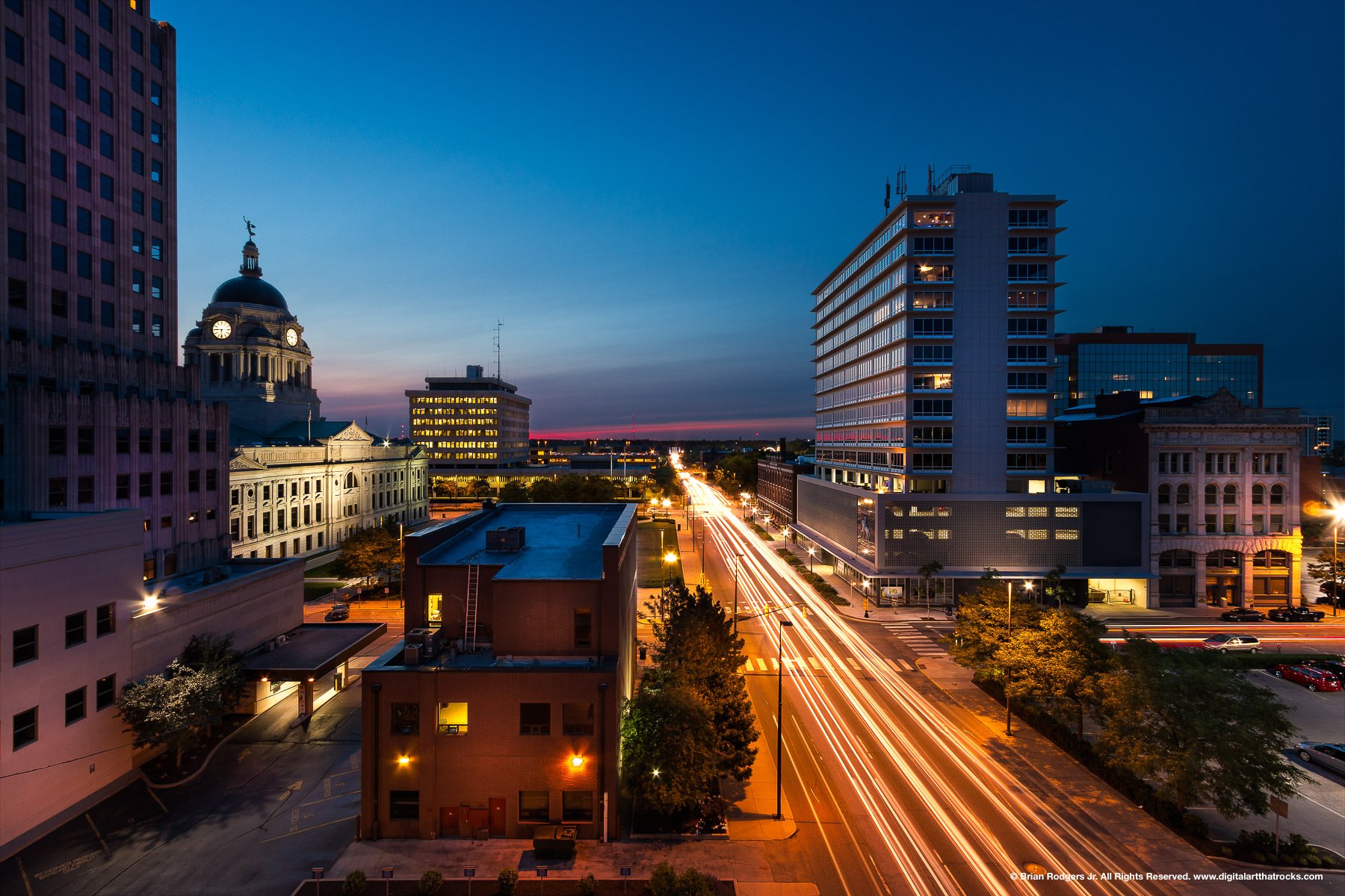 Twilight cityscape photography of Fort Wayne, Indiana downtown featuring light trails, historic architecture, and urban density, created for city branding, tourism boards, and urban planning firms.