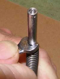 Slide the spring from your present plastic guide rod over the steel guide rod and compress it as shown. A wrench as shown may help but the job can easily be done by hand.