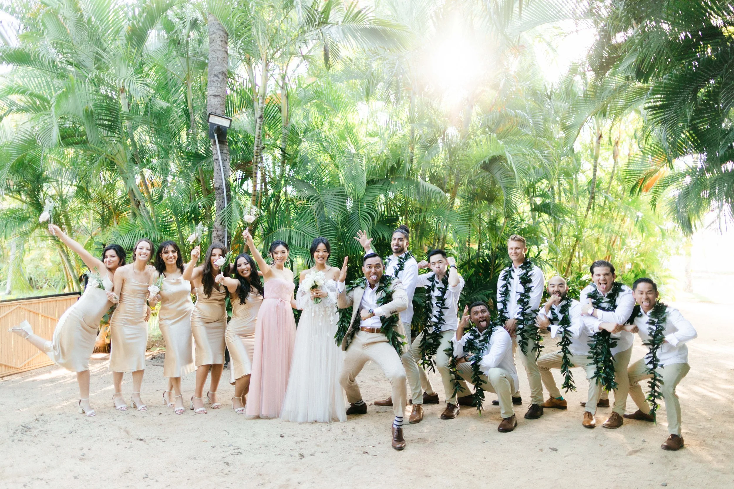 Wedding party celebrating outdoors in Hawaii, with the bride and groom surrounded by friends and family.
