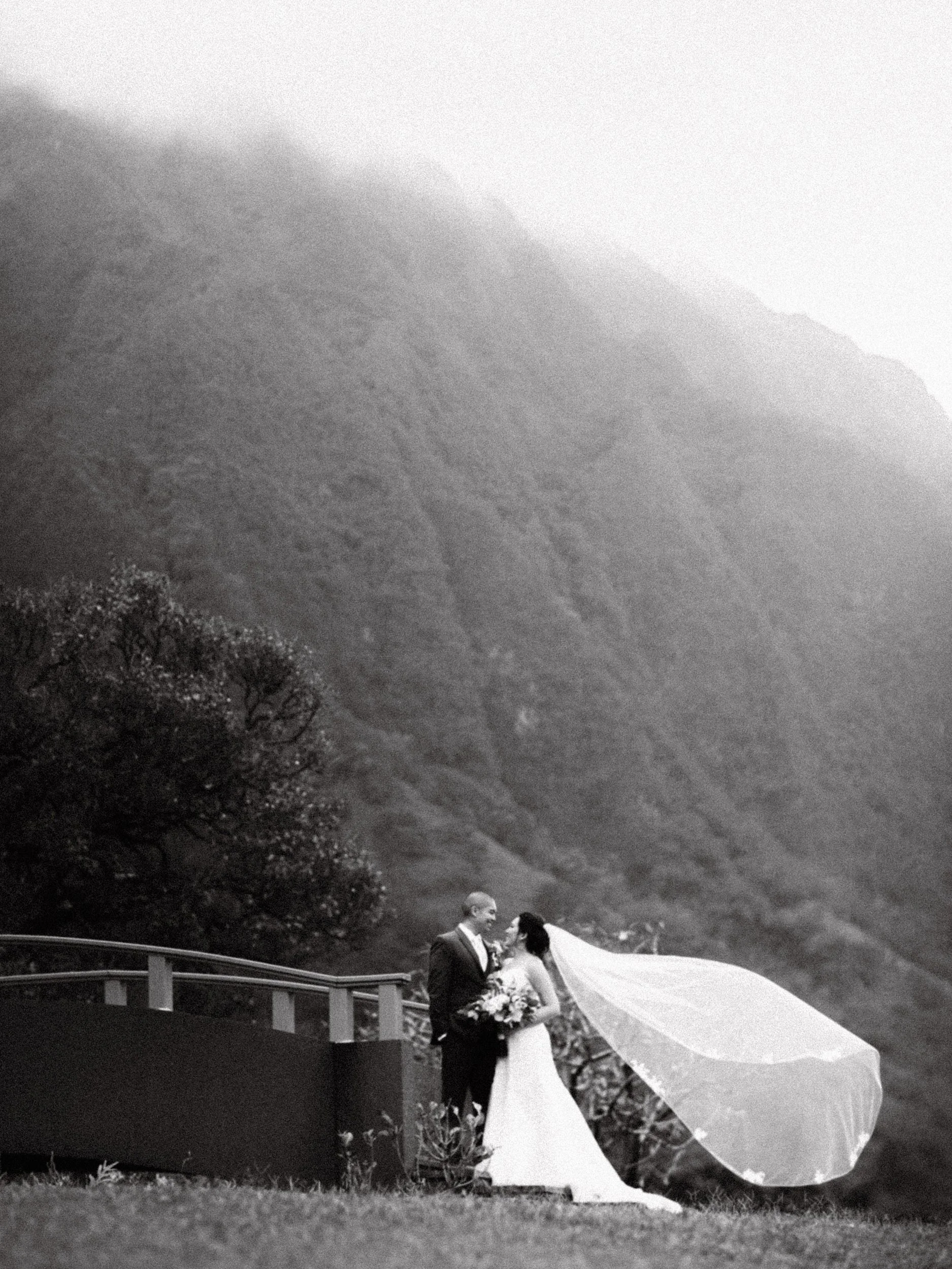 A couple standing before the dramatic Koolau mountain peaks of on Oahu