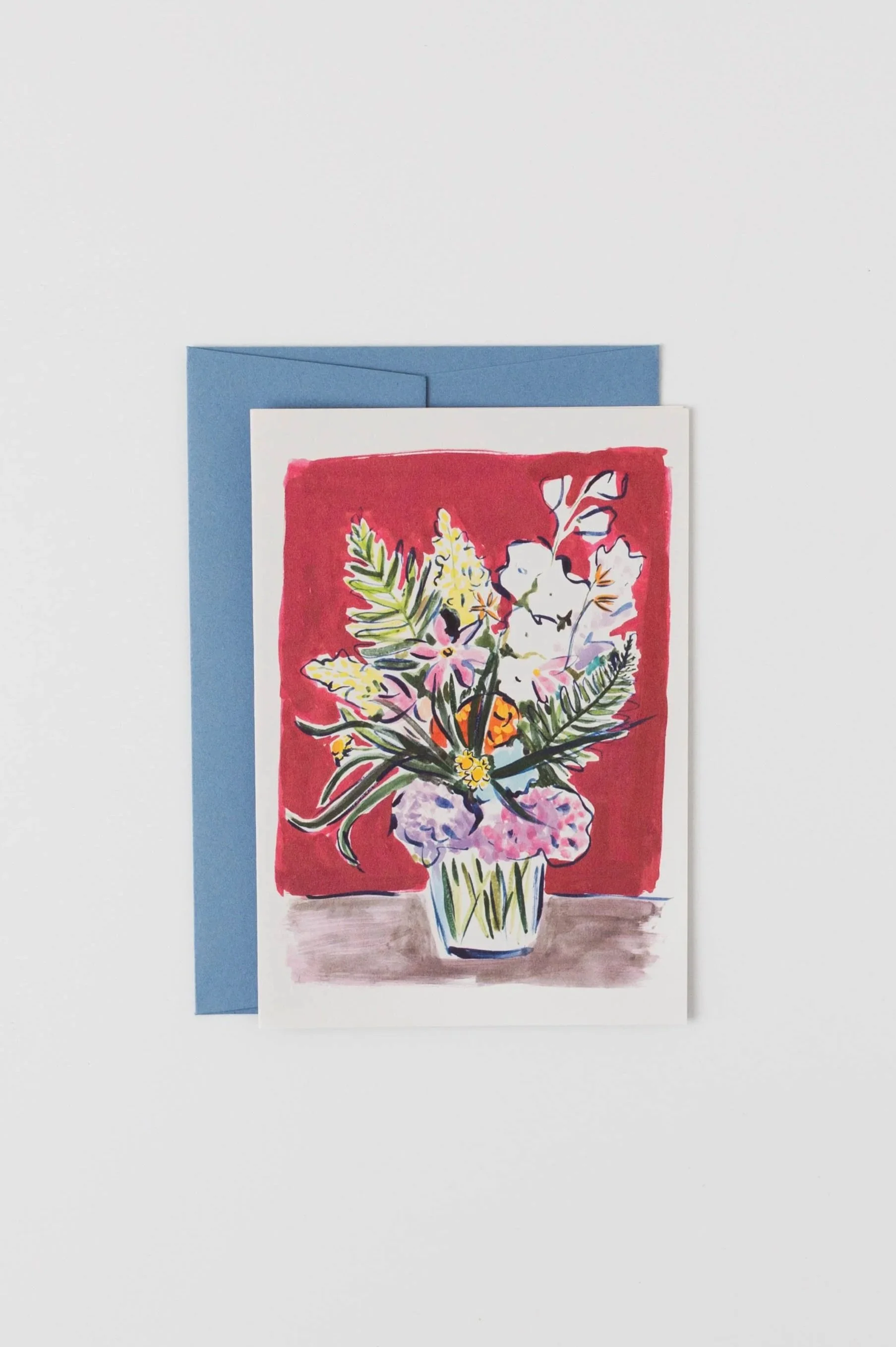 A greeting card featuring a loose, painterly illustration of a floral vase with fresh greens, white blooms, and hydrangeas in a cheerful display.