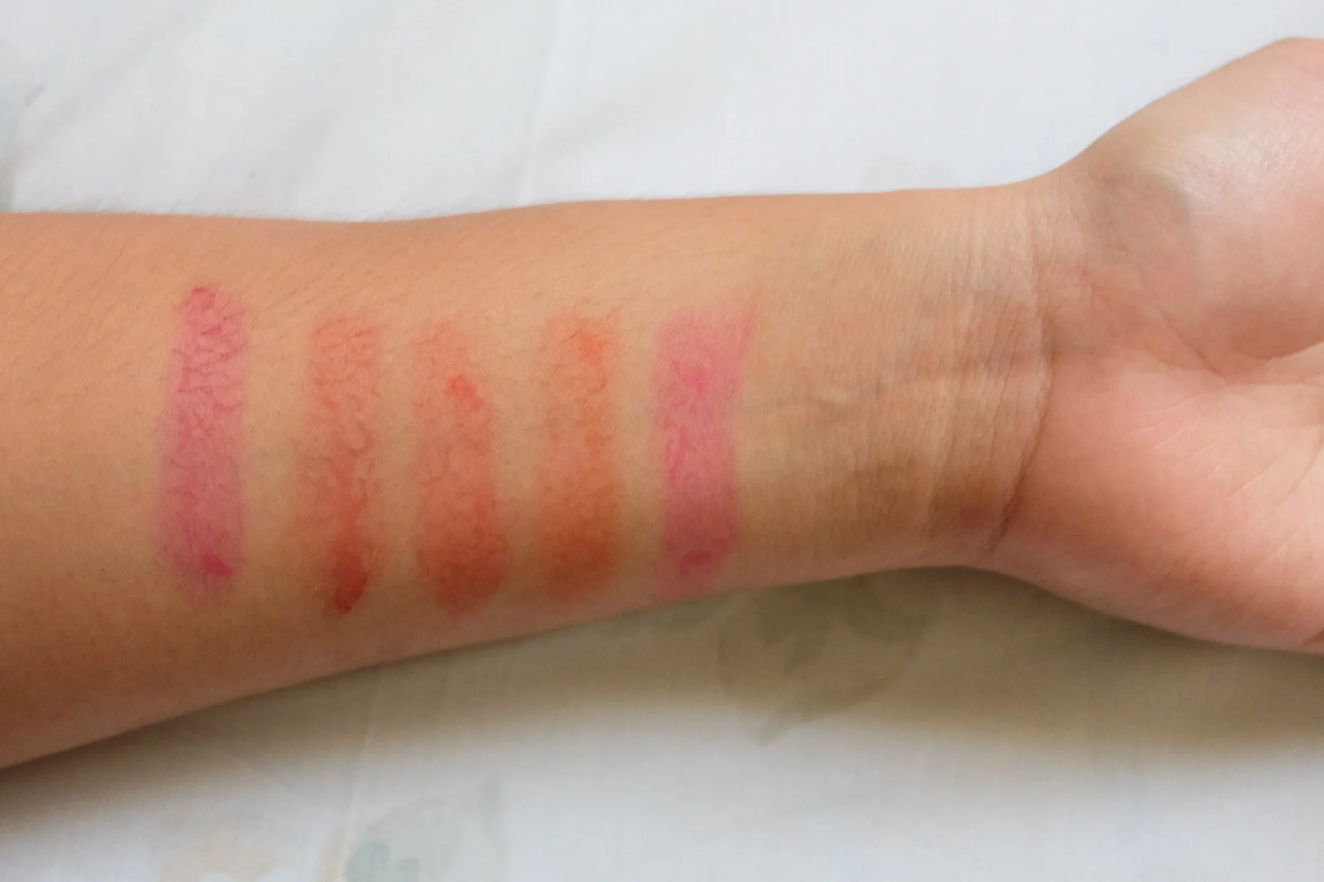 Swatches on my morena skin: Fused, Bittersweet Magenta, Bloodshot, Summer Kiss, and Dolled