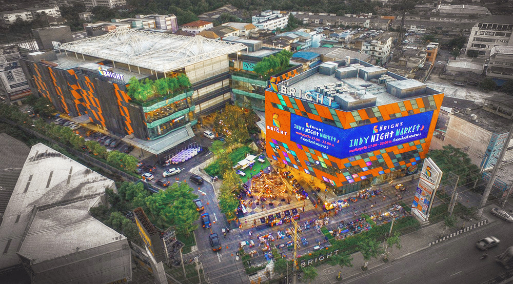 5-storey Office Tower, 3-storey Mall and 7-storey Parking Building Program : Mixed Use Area : 35,200 sq.m. Location : Rama 2 Road, Bangkok, Thailand Status : Completed Client : Lampton Property Co., Ltd Project Director : Punpong Wiwatkul Project Team : Piboon Amornjiraporn, Thitipan Chueasawad, Collaborator : Creative Crews The mixed development is located at Rama2 road, an outskirt of Bangkok. The development will be the head office of the owner who is the light manufacturing company, and there will be open-air community mall for the area. The office building is located along the main road in order to comply with the urban regulation. The podium consists of shopping mall, food court, show room and auditorium while the tower is the headquarter office. The podium mass is visually separated into 2 parts by crystal-like façade to allow for natural light for at waiting area of auditorium, food court and main escalators. The orange colour façade and crystal-like curtain wall are proposed to capture the sense of the cooperate identity and create liveliness to the development. The community mall is 4-storey with the series of shops, open-air corridors and plaza. The massing is split to create in between spaces and allow for natural ventilation throughout the whole building. The jet fans are also incorporated along the corridors to stimulate the wind and create the comfortable atmosphere for users. The glass balustrade and crystal-like façade which are used at the community mall carries the similar design with the façade used at the office atrium. The tensile fabric roof are used to provide shades and comfort environment to the plaza in the center. The design balanced between energy concerns and creating the lively vibe.