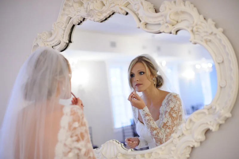 bride touches up her make up in the mirror at the villa blanca
