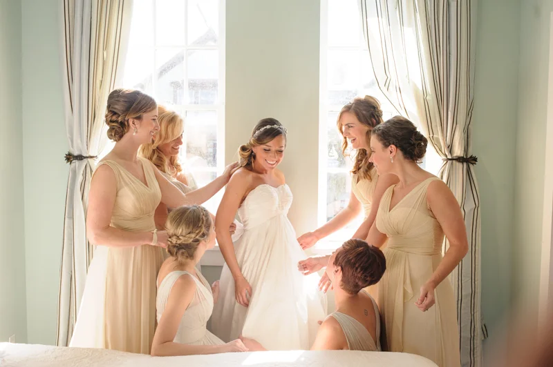 the bridesmaids put on the finishing touches to the bride just before her ceremony at the White Room in St. Augustine, Florida