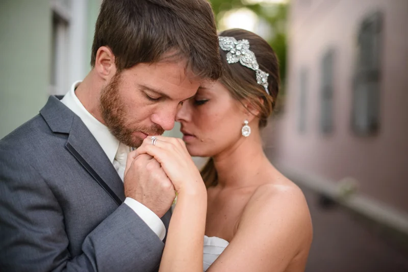 groom gently kisses his new brides hand just downstairs from the White Room in St. Augustine, Florida