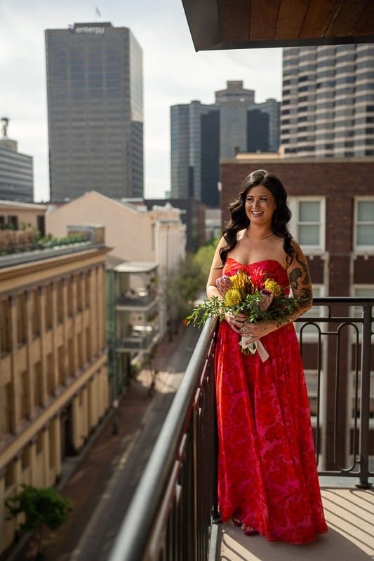 0012_Woman in a red dress holding a bouquet on a city balcony with skyscrapers in the background.jpg