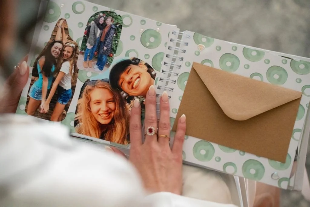 A person looks at a scrapbook filled with cheerful photos and an envelope.jpg