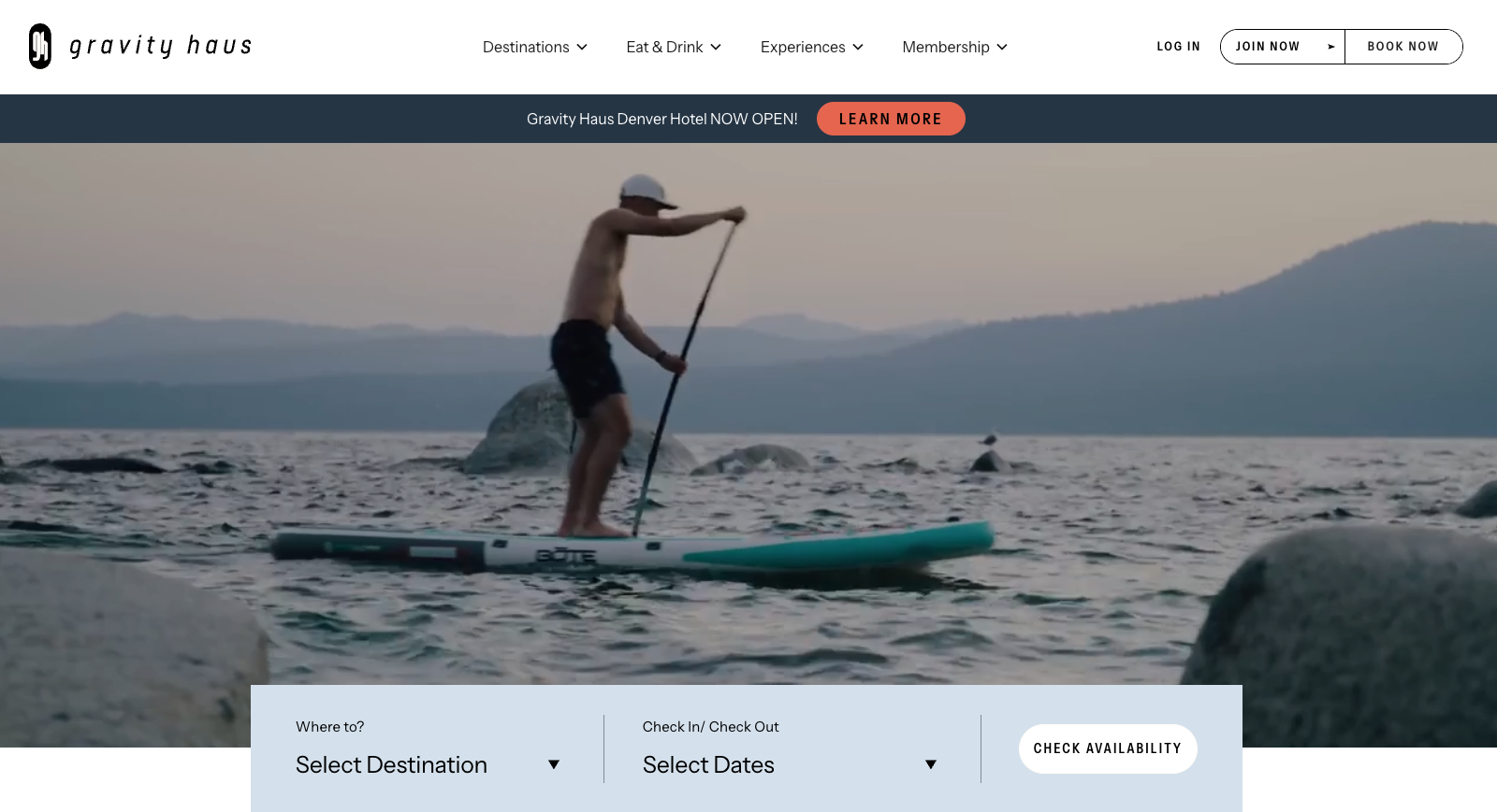Gravity Haus hotel website homepage. A striking image of a young man stand-up paddle-boarding on a serene mountain lake.