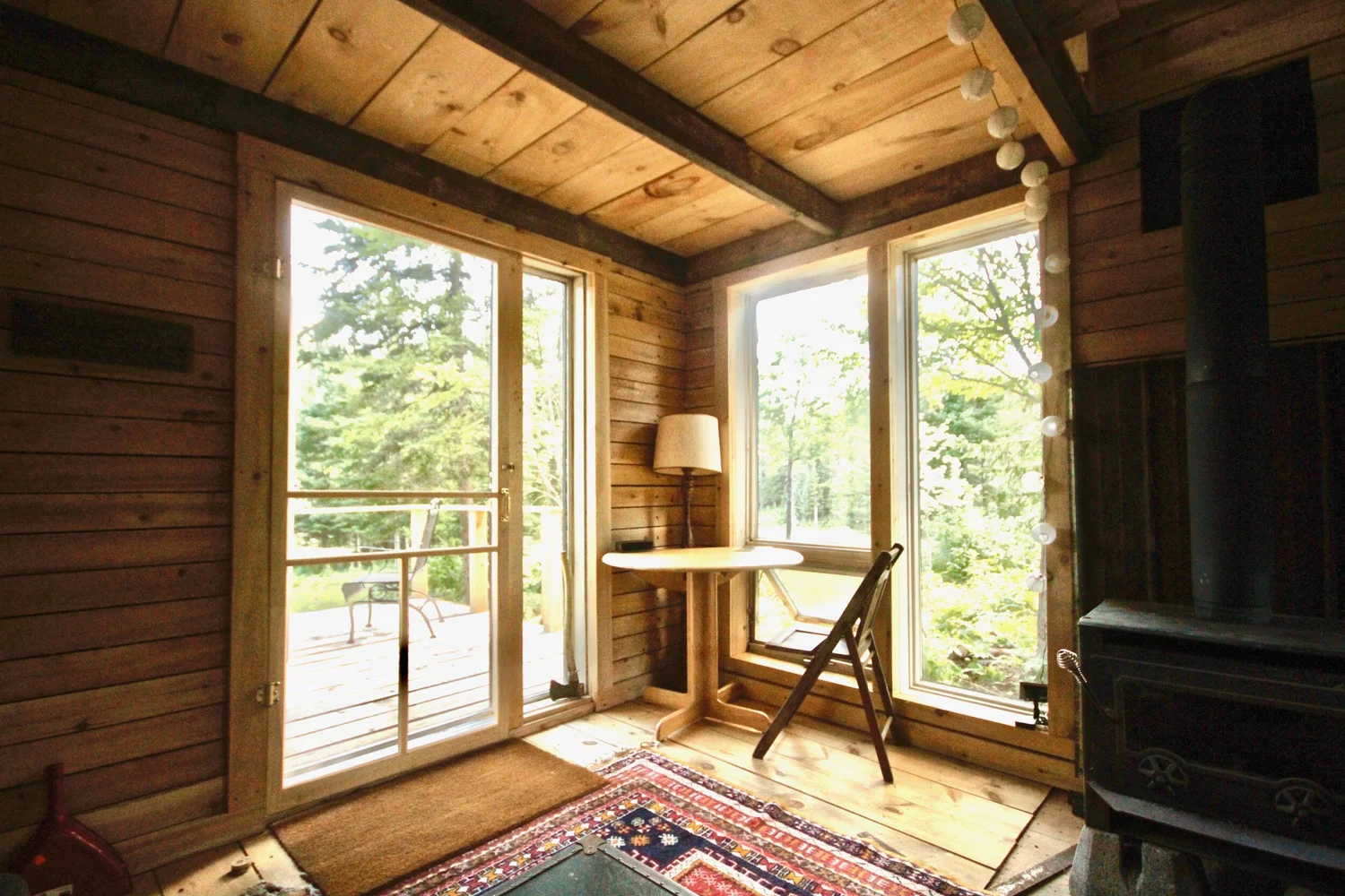 Portes vitr&eacute;es sur la terrasse, une petite table ronde pr&egrave;s de la fen&ecirc;tre du coin, et le po&ecirc;le &agrave; bois