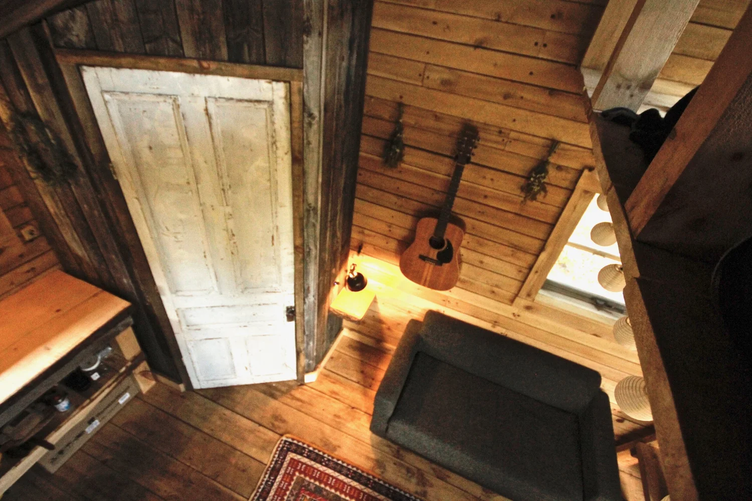 Vue sur la pi&egrave;ce principale depuis la mezzanine&nbsp;: la porte, le divan et le comptoir