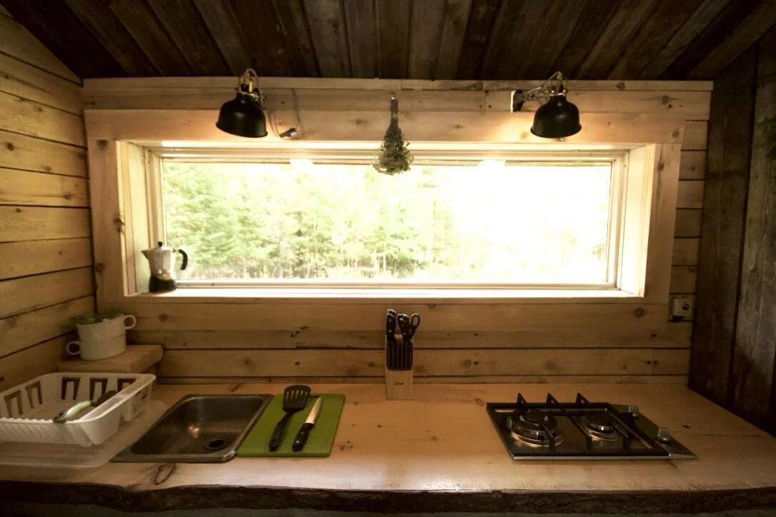 Le comptoir de cuisine&nbsp;: &eacute;vier, cuisini&egrave;re au propane &agrave; deux br&ucirc;leurs et cafeti&egrave;re italienne sous une longue fen&ecirc;tre